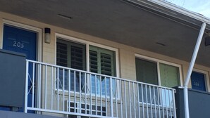 Un edificio con puertas numeradas, un balcón con barandilla blanca y una ventana con diseño de cuadrícula.