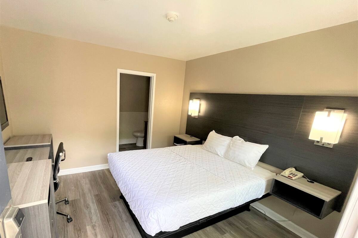 Una habitación de hotel con cama, mesita de noche y espejo.