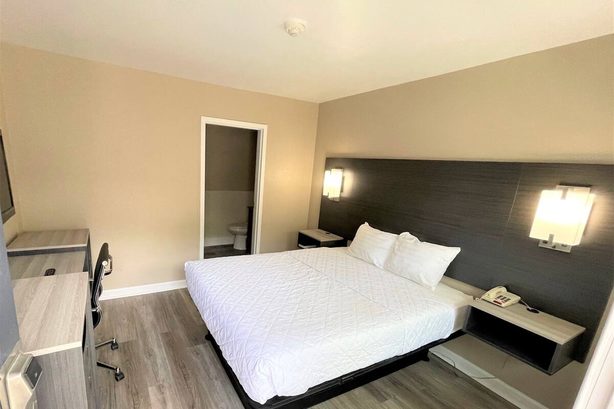 Una habitación de hotel con cama, mesita de noche y espejo.