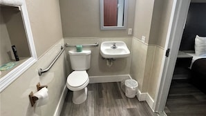 Ein kleines, modernes Badezimmer mit Toilette, Waschbecken und Spiegel.
