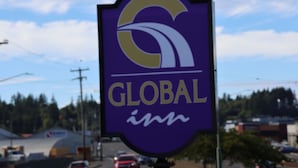 A purple sign with a gold logo and the word "GLOBAL" on it. - Global INN (Coos Bay)