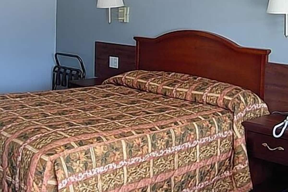 A hotel room with a wooden bed, two bedside lamps, and a chair.