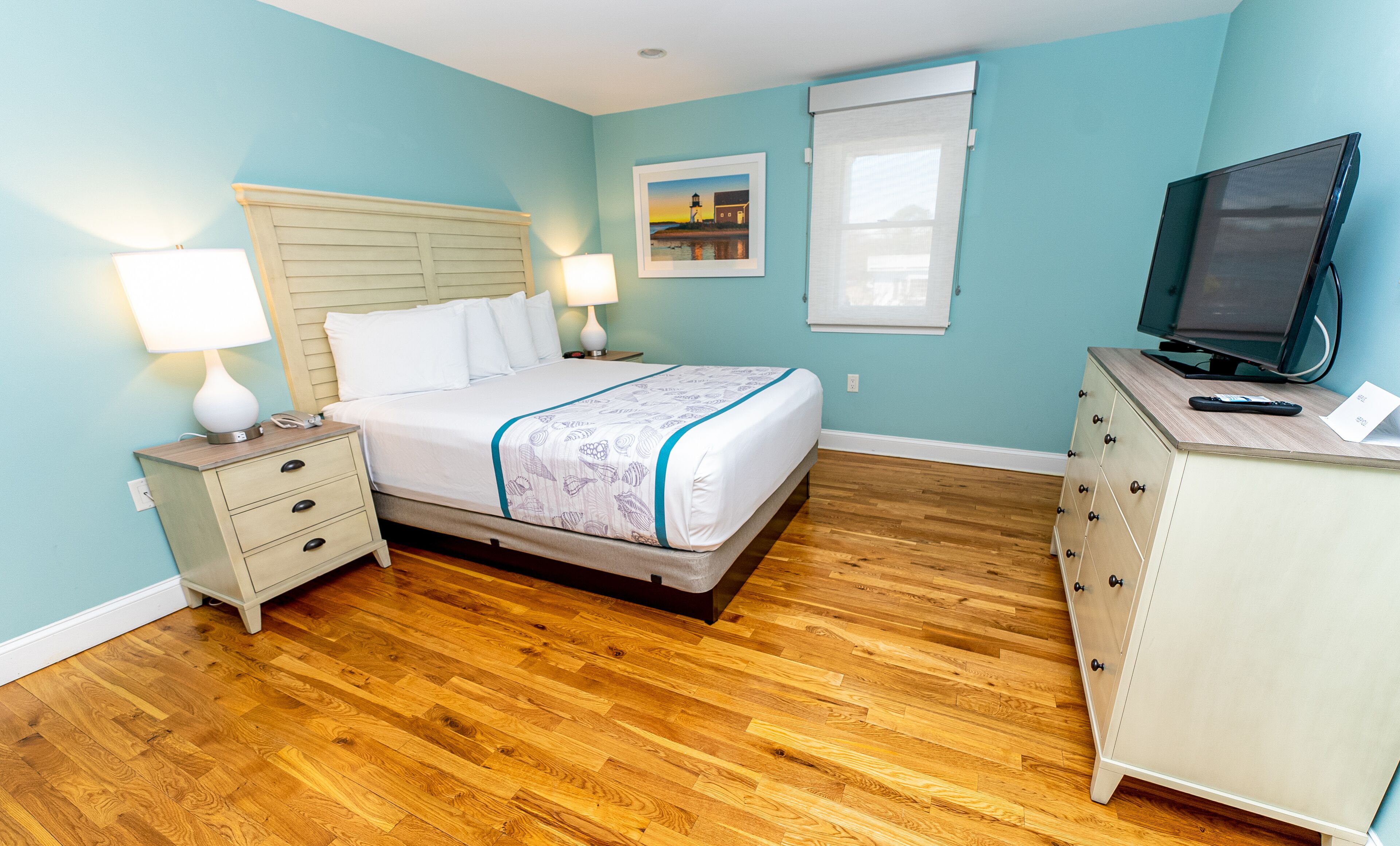 Une chambre à coucher comprenant un lit, des tables de chevet, une commode, un téléviseur et une fenêtre.