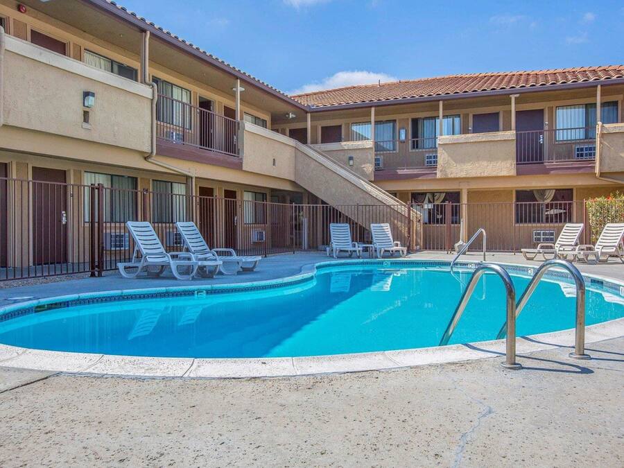 Um hotel com piscina, várias varandas e espreguiçadeiras.