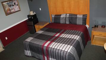 Una habitación de hotel con una cama grande, cabecera de madera, mesita de noche, escritorio y lámpara de pared.