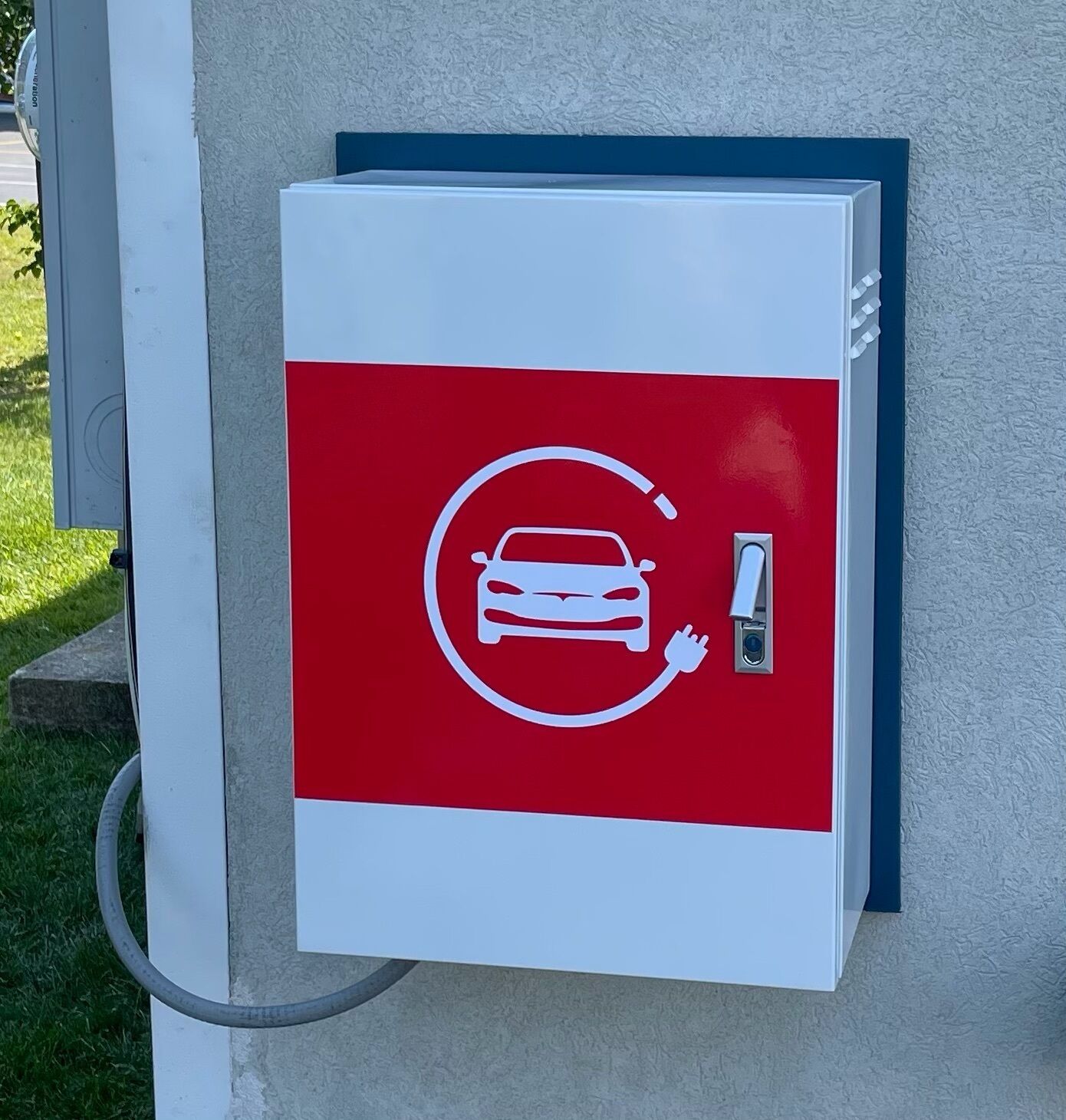 A red and white electric vehicle charging station with a cable connected to it.