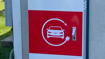 A red and white electric vehicle charging station with a cable connected to it.