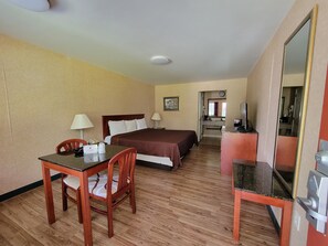 A hotel room with a bed, desk, chair, and a television.