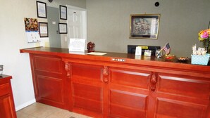 A reception desk with a wooden finish, a framed picture on the wall, and a small American flag.