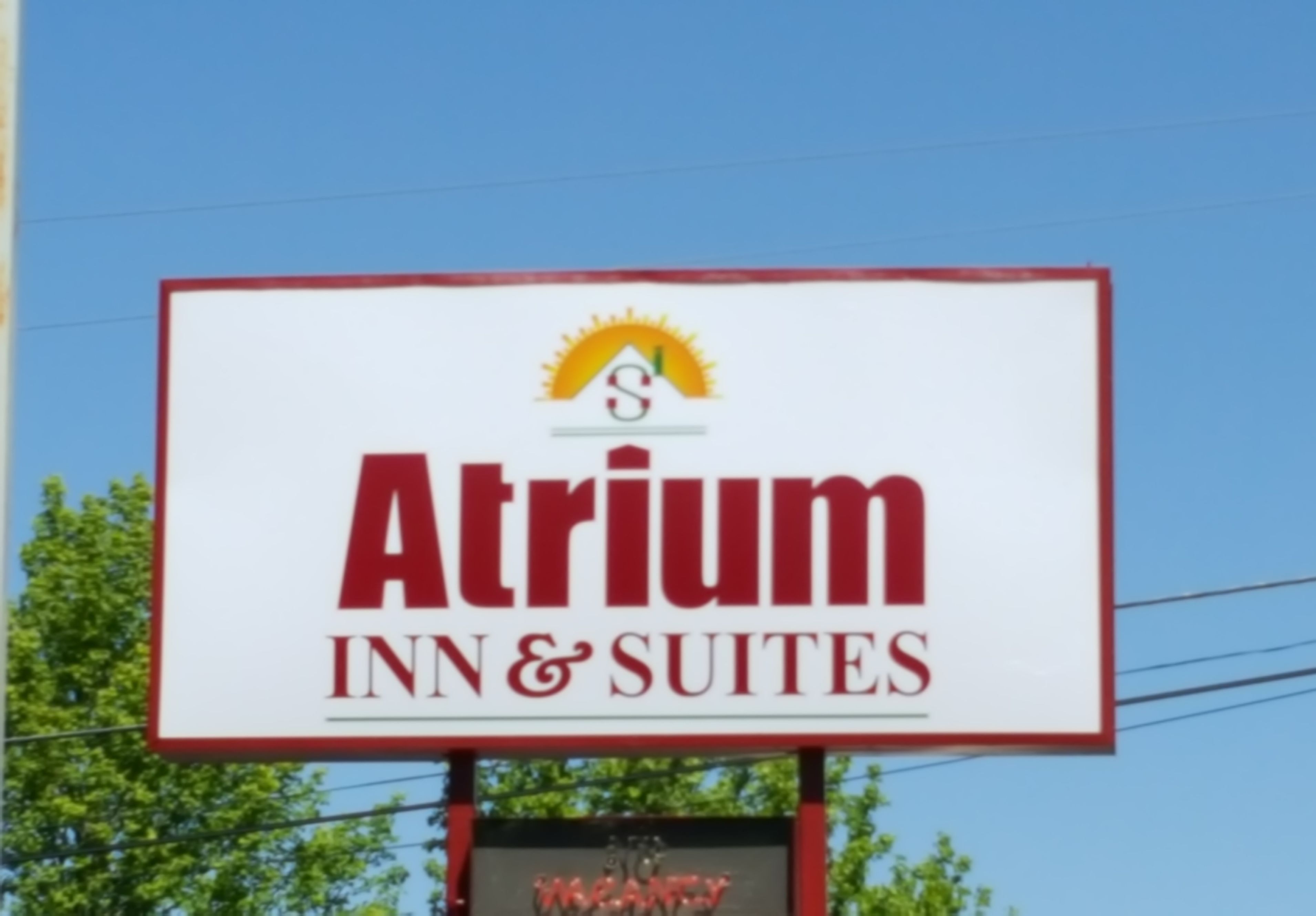 Senyal per a l'Atrium Inn & Suites amb un logotip de sol i una vora vermella.