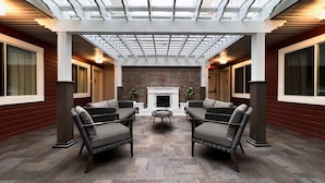 A covered patio with wicker furniture, a fireplace, and a stone wall. - The Downtown, a Coast Hotel (Dawson City)