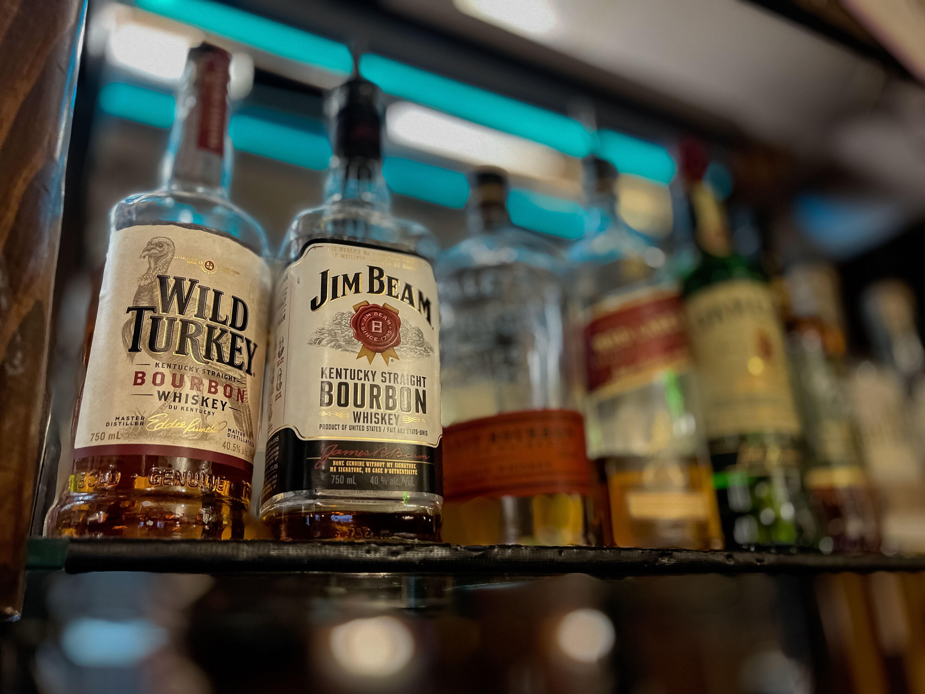 Flaschen von Wild Turkey und Jim Beam Bourbon Whiskey auf einem Regal.
