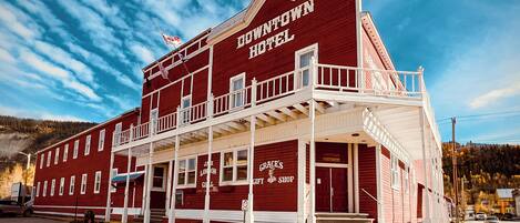 A two-story red building with a balcony, labeled "Downtown Hotel," featuring a gift shop and a sign for "Grace's Gift Shop."