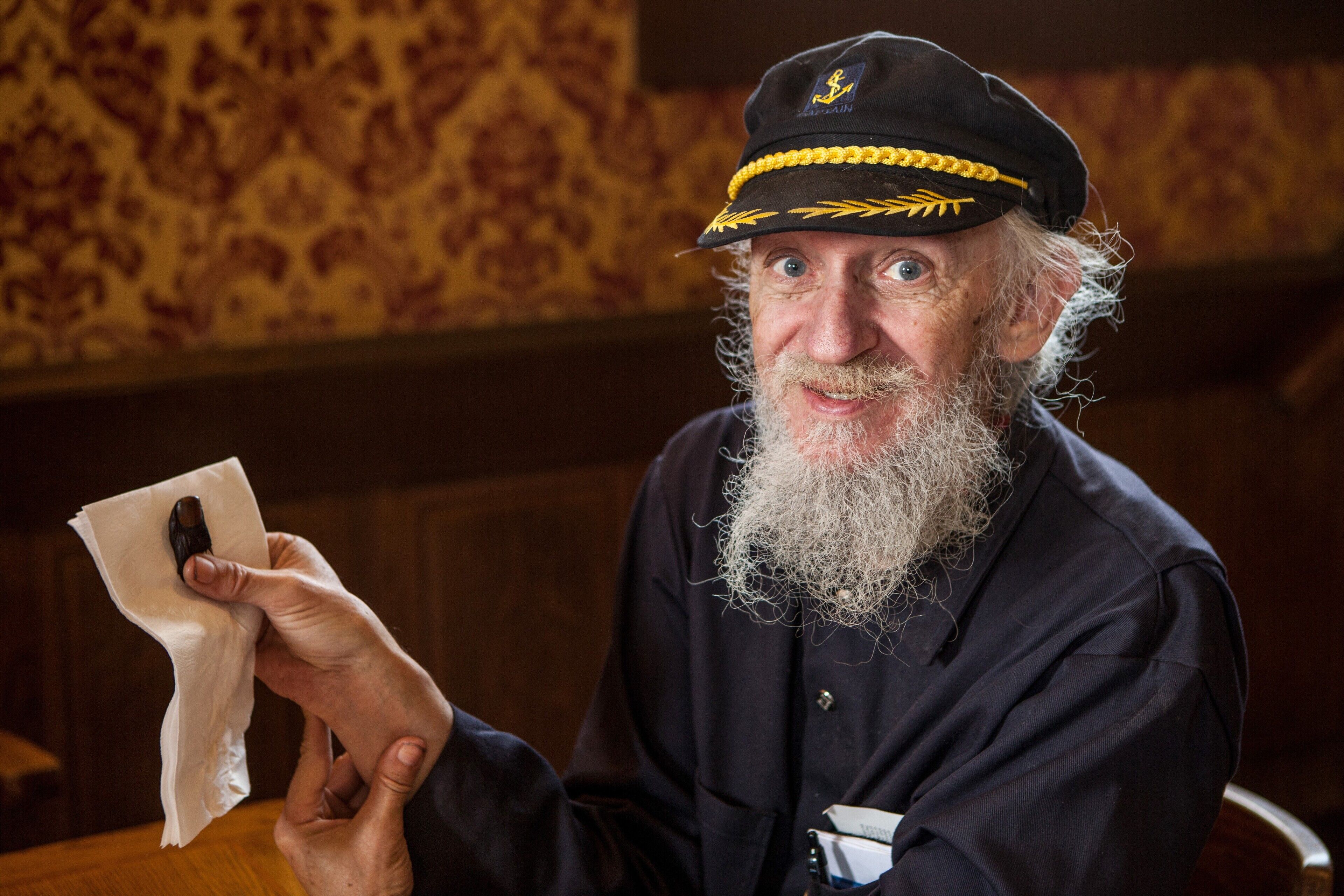 A person in a dark uniform with a cap, holding a piece of paper.