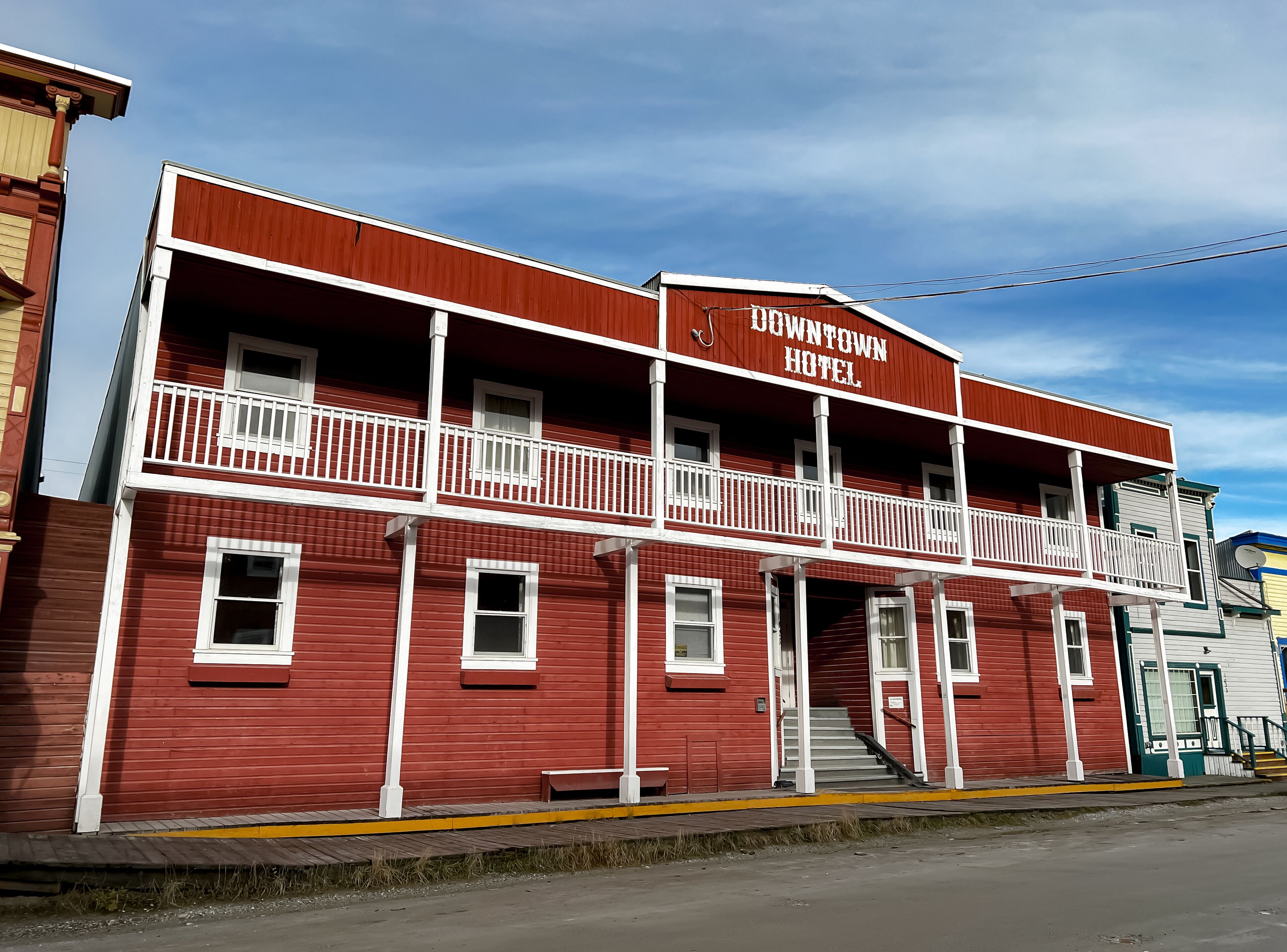A red building with a balcony and a sign that reads "Downtown Hotel".
