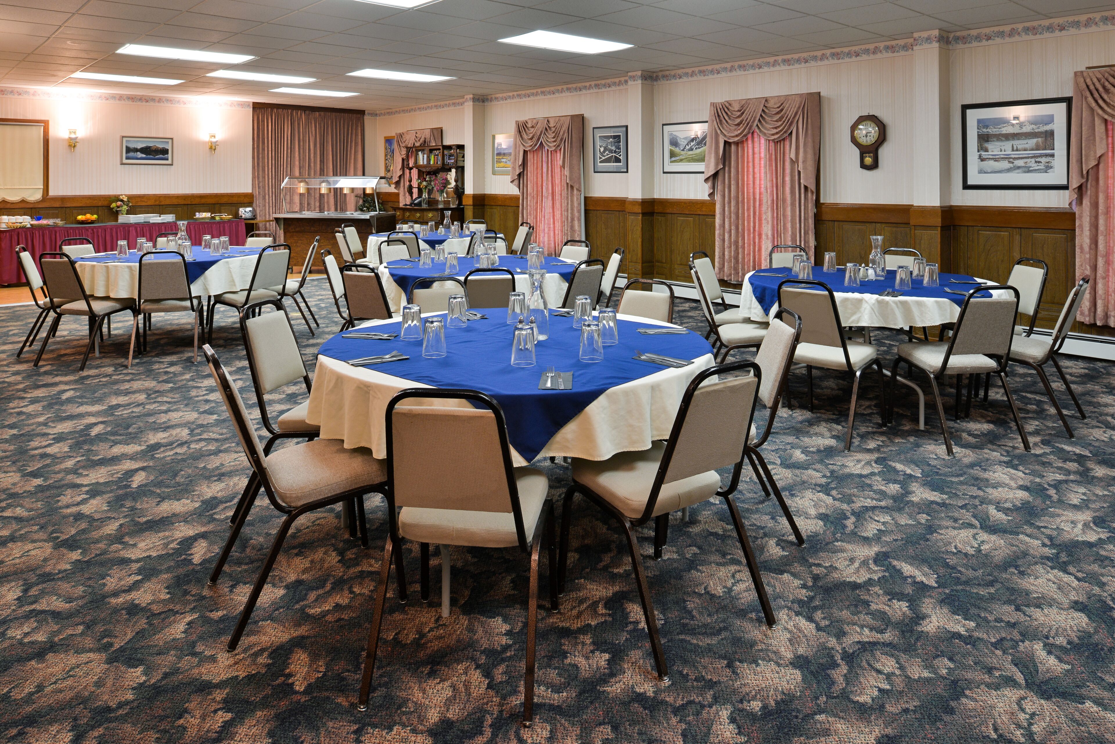 A conference room with round tables, chairs, and a buffet area.
