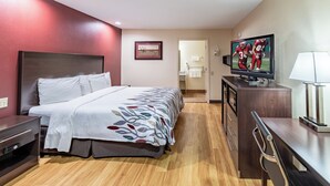 Une chambre d’hôtel avec un lit, une télévision, un bureau et une salle de bain visible à travers une porte ouverte.