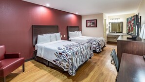 A hotel room with two beds, a TV, a desk, and a red wall. - Red Roof Inn Buffalo, TX (Buffalo)