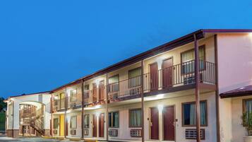 A multi-story motel with a central staircase, balconies, and a parking lot.