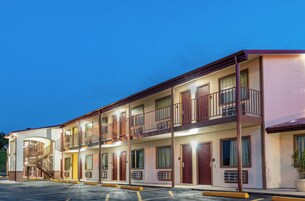 Un motel de varios pisos con una escalera central, balcones y un estacionamiento.