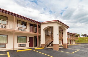 A multi-story motel with a central atrium, outdoor parking, and a small hill with a gazebo in the background. - Red Roof Inn Buffalo, TX (Buffalo)