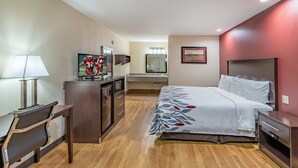 A hotel room with a bed, a desk with a lamp, a TV, a mirror, and a dresser. - Red Roof Inn Buffalo, TX (Buffalo)