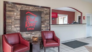 A Red Roof Inn reception area with two leather chairs, a stone wall backdrop, and a sign indicating free Wi-Fi in all rooms. - Red Roof Inn Buffalo, TX (Buffalo)