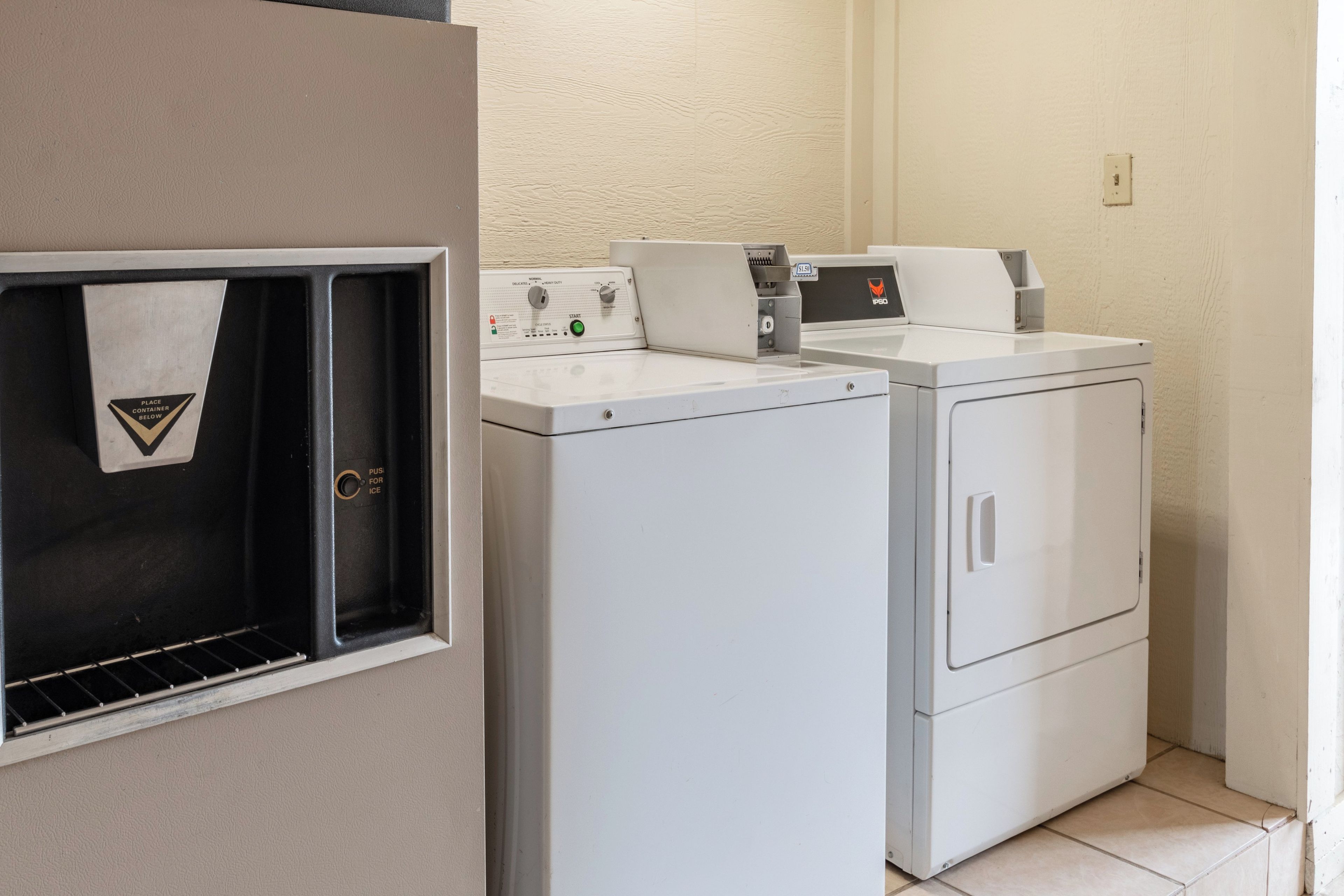 A laundry area with two front-loading washing machines and a dryer, a towel rack, and a control panel with a timer.