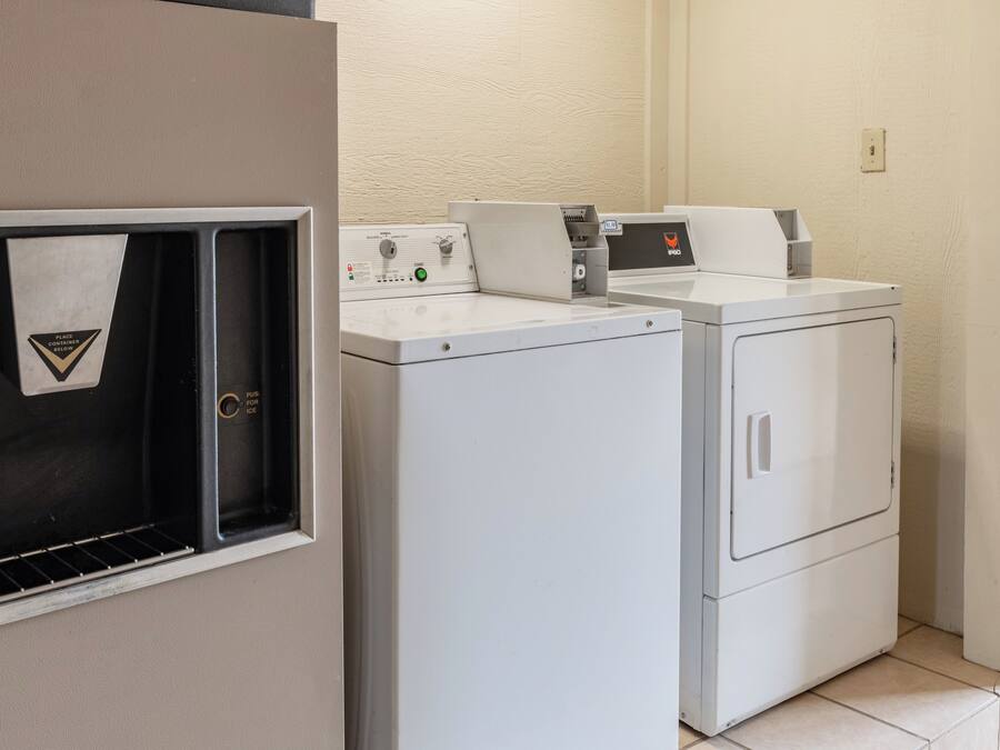 A laundry area with two front-loading washing machines and a dryer, a towel rack, and a control panel with a timer.
