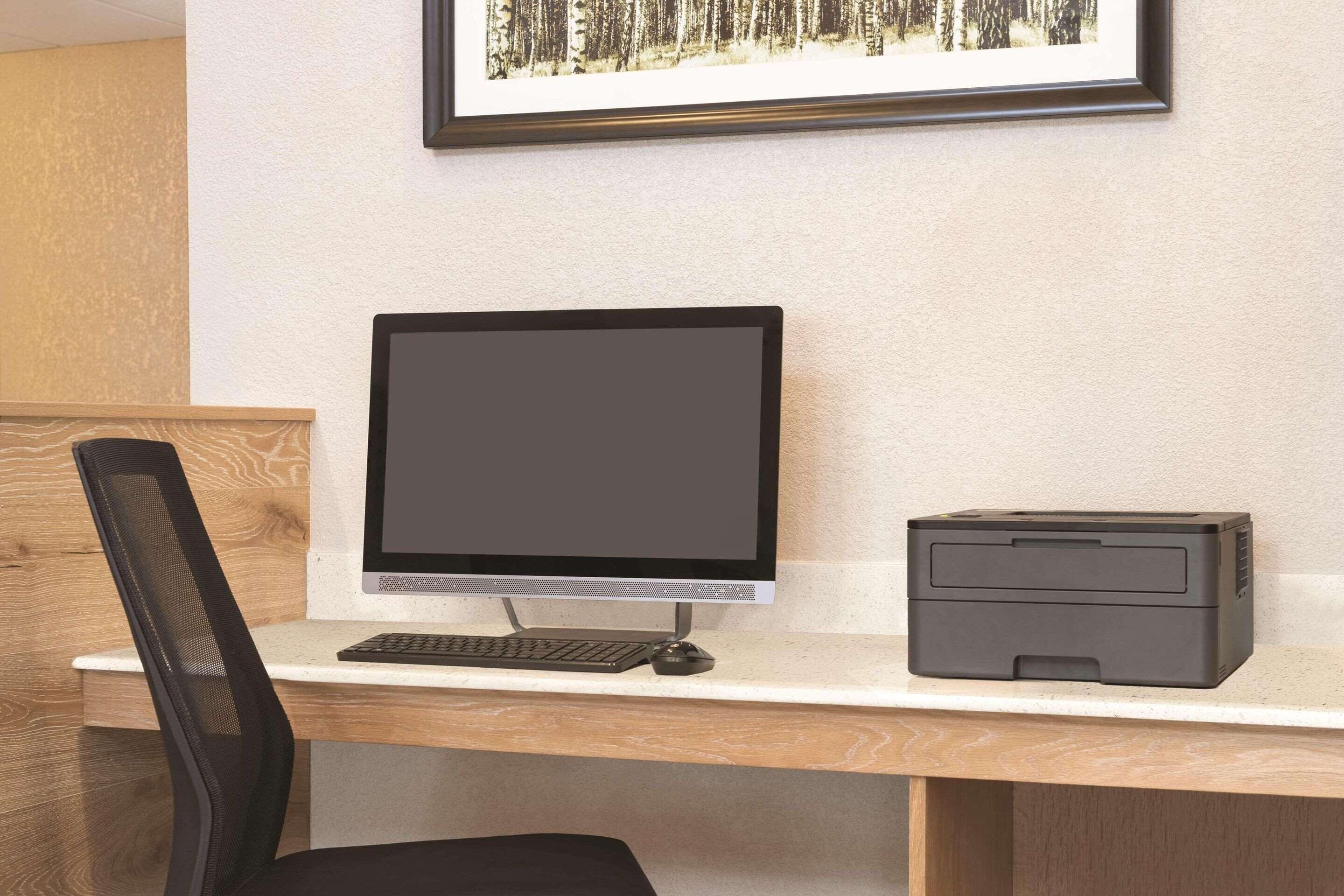 A desk with a computer monitor, keyboard, and printer.