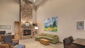 A living room with a stone fireplace, green sofa, wooden coffee table, and a painting on the wall.