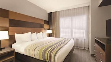 A hotel room with a large bed, a wooden headboard, a TV, a nightstand, and a window with curtains.