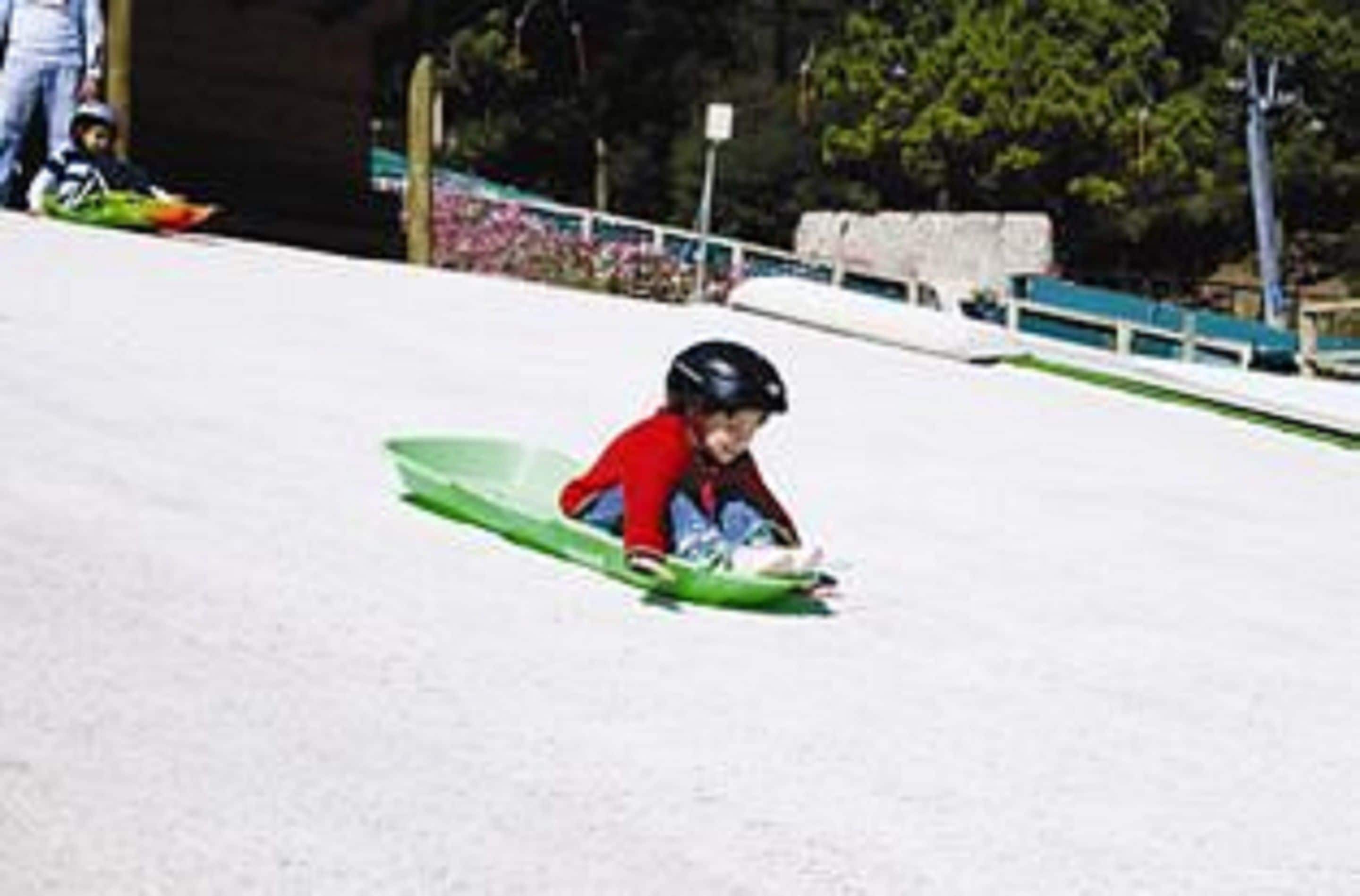 Un niño bajando una colina nevada en trineo.