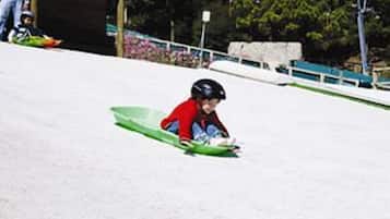 Un niño bajando una colina nevada en trineo.