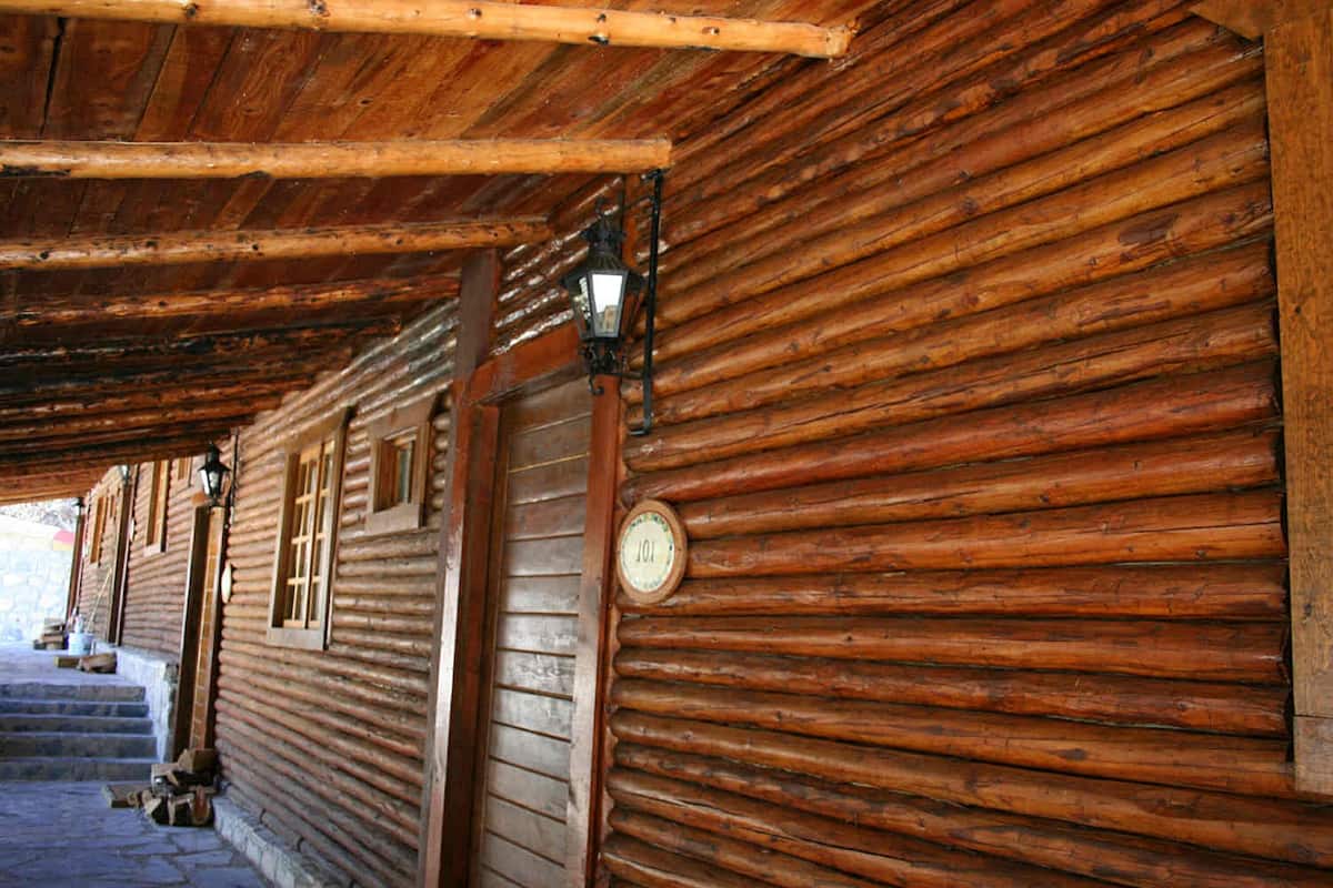 A log cabin with a wooden exterior, a stone-paved entrance, and a lantern above the door.