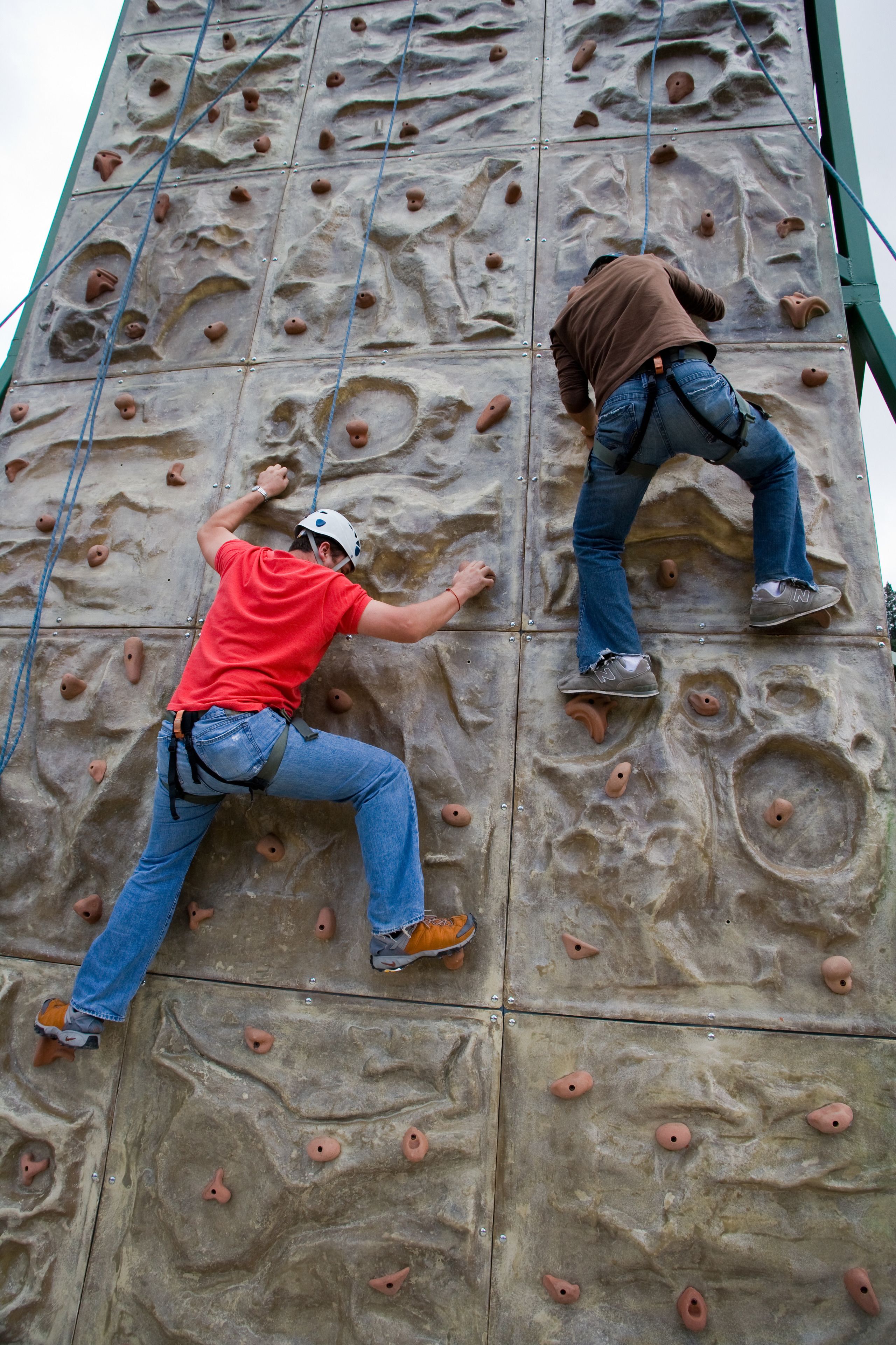 A person climbing a large rock wall with handholds and footholds.