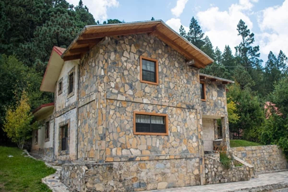 A stone house with a sloped roof, a small porch, and a stone wall foundation.