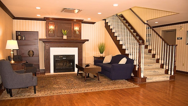 A living room with a fireplace, a staircase, and a dining area.
