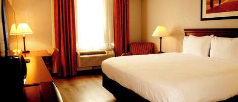 Un cuarto de hotel con una cama grande, dos mesitas de noche con lámparas, una ventana con cortinas y un cuadro en la pared.