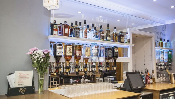 Un espace bar équipé de plusieurs distributeurs de boissons alcoolisées et d’une caisse enregistreuse.