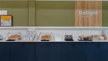 A modern kitchen with a breakfast bar, featuring a sign that reads "Delight in the day," and a variety of breakfast items displayed.