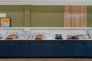 A modern kitchen with a breakfast bar, featuring a sign that reads "Delight in the day," and a variety of breakfast items displayed.