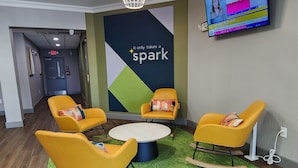 A modern lounge area with yellow chairs, a central round table, and a motivational wall. - Spark by Hilton Rahway (Rahway)
