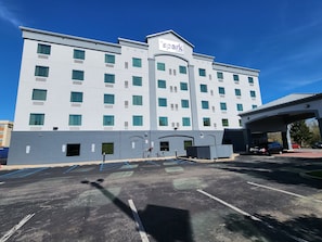 Um hotel moderno com a placa 'Spark by Hilton', estacionamento e área de entrada coberta.