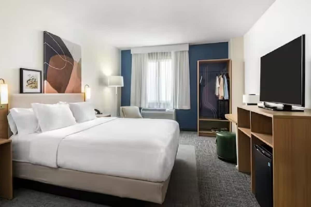 Ett hotellrum med en stor säng, en garderob, en tv och ett skrivbord.