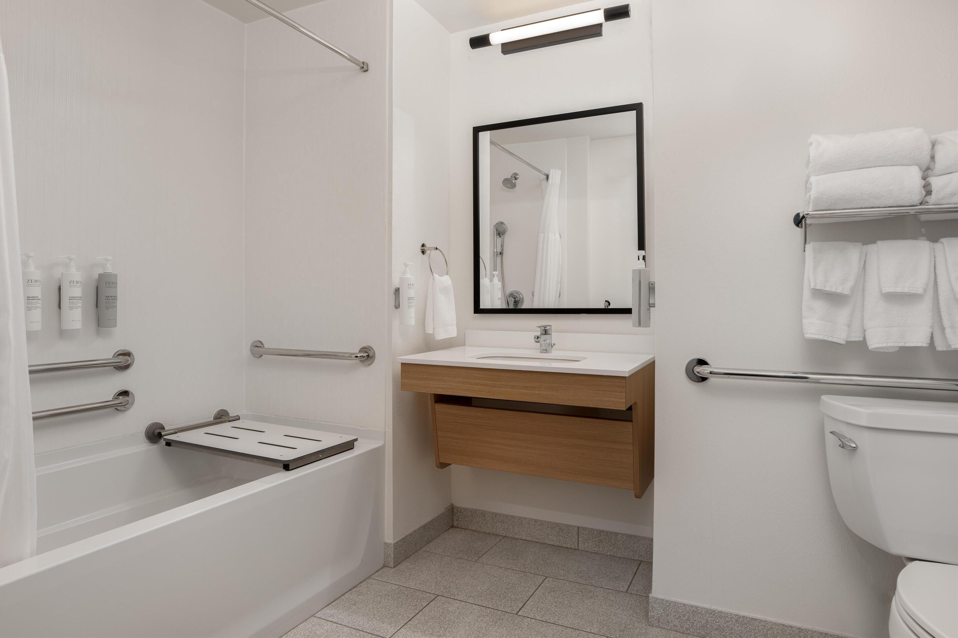Un baño moderno con bañera, lavabo con espejo e inodoro.