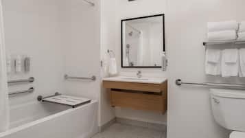 Un baño moderno con bañera, lavabo con espejo e inodoro.
