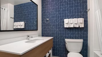 Une salle de bain avec un lavabo blanc, un miroir, des toilettes et des carreaux bleus à motifs.