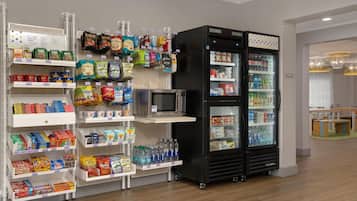 Area espositiva con snack e bevande, dotata di forno a microonde e frigorifero.