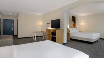 A hotel room with a large bed, a desk with a chair, a television, and a small table.
